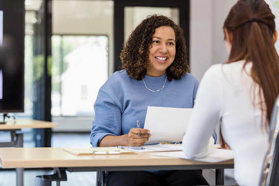 two businesspeople sitting at desk talking through papers