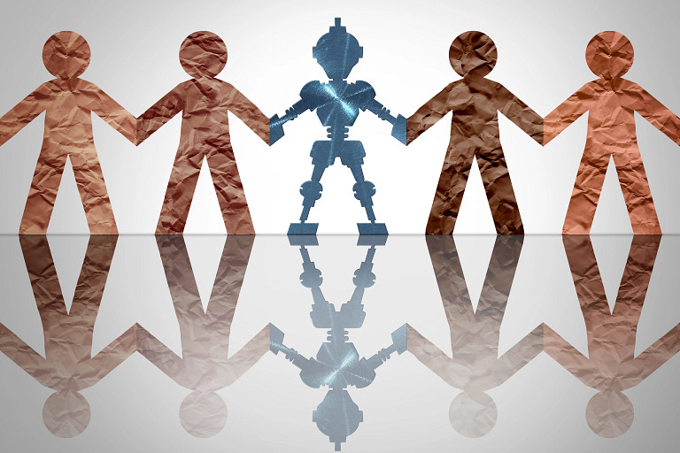 Five paper-cutout figures stand hand in hand on a reflective surface. Four are brown, while the central figure is blue and robotic, suggesting technology or AI among humans. A soft gray background emphasizes unity and contrast between humans and machines.